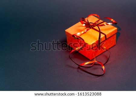 Gift box with red ribbon on a gray background. Red backlight