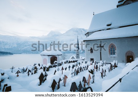 Famous Hallstatt lakeside town with church tower and graveyard on a beautiful cold morning in winter, Salzkammergut, Austria