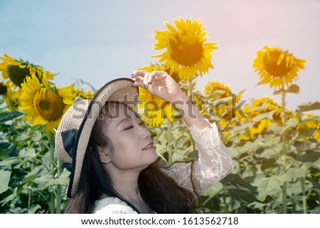 Portrait of pretty Asian women are fun, happiness and pose in a variety of gestures. In sunflower planting fields. 