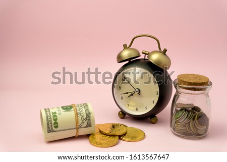 Time to make money concept, pink retro styled alarm clock on heap of american dollars. Banking, Savings, Wealth.