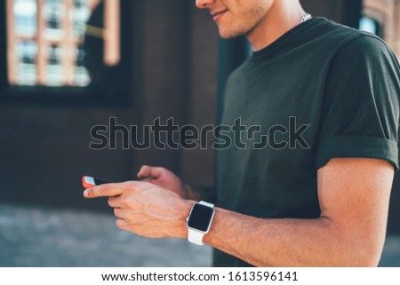 Cropped view of male blogger installing application on modern smartphone using 4G internet connection, millennial man holding new mobile phone in hands and chatting online on cellular device