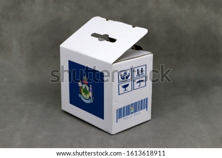 Maine flag on white box with fragile symbol and barcode on grey background. The concept of export trading from Maine. Paper packaging for put products.