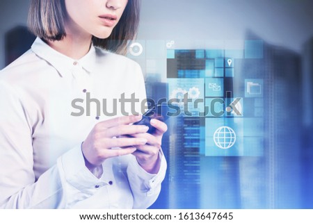 Unrecognizable young businesswoman working with smartphone in blurry city with double exposure of business interface. Concept of internet connection. Toned image