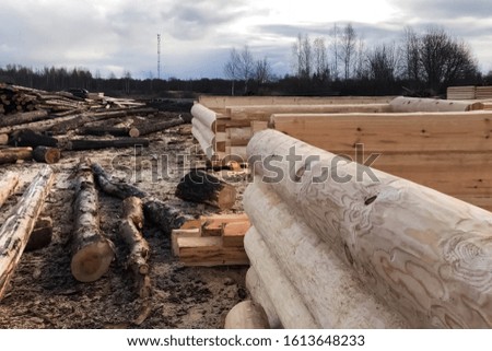 Preparation of logs for the assembly of the structure. Materials for a wooden house. Drying and assembly of a wooden log house at a construction base.