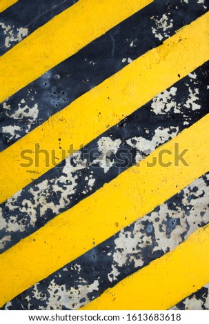 Safety stripes. Warning stripes. Yellow and black diagonal lines on the concrete surface. Cracked surface. 