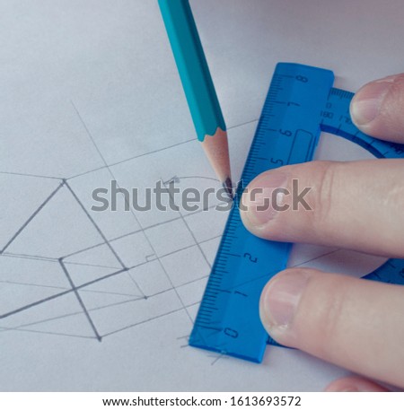 A man draws a scheme on white paper with a pencil using a ruler. Drawing project in pencil on a large sheet of close-up.