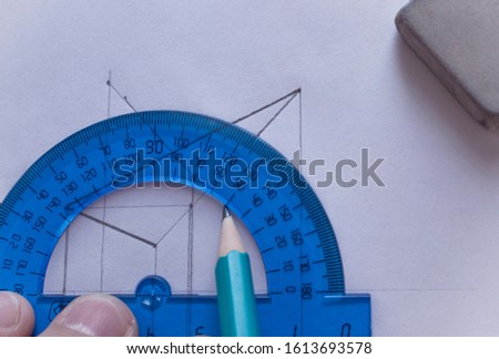 A man draws a diagram with a ruler, eraser and pencil. Design and create a project on a white sheet of paper close-up.
