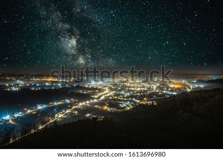Starry sky over a night city in the Carpathian mountains