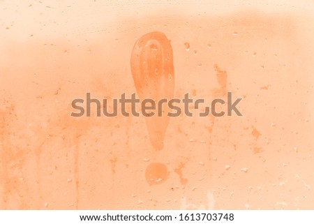 The exclamation mark or exclamation point picture or figure on the orange or pink evening or morning window glass with drops