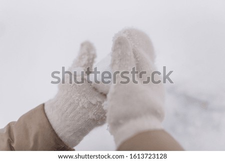 Woman makes a snowball in the hands of white mittens