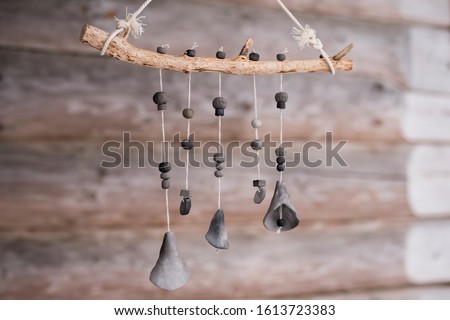 Unique handmade wind chime made of branch and black ceramic bells on log house background Royalty-Free Stock Photo #1613723383