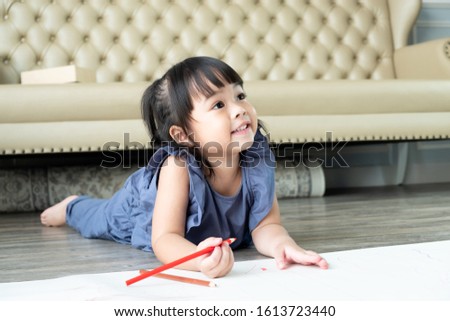 Beautiful Asian toddler girl 3 years old enjoy drawing and learning how to write in the living room at home. Preschool learning activity concept.