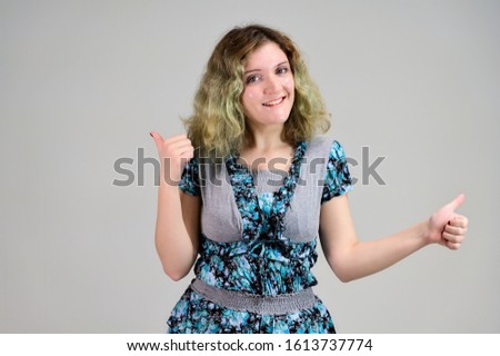Concept horizontal photo of a young woman with emotions in a turquoise dress stands in front of the camera on a white background. Portrait of a student girl with beautiful magnificent hair.