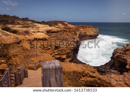 Path leading to a cave washed out by the agitated sea beating the cliffs