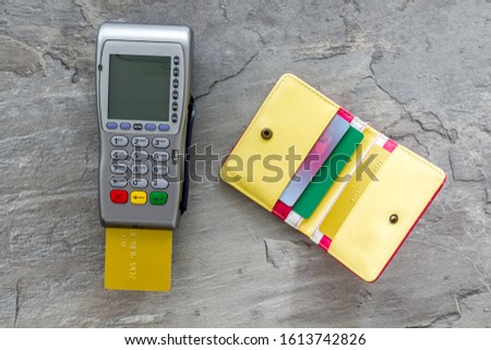 Pay by credit card in shop. Terminal and card on grey stone background top-down