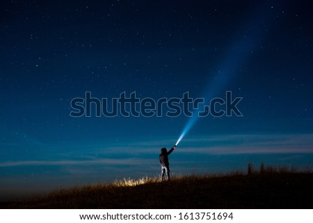 Milky Way.Long exposure photography, a
 man holding a flashlight and illuminating the sky full of stars. Image soft focus and noise due to long expose and high iso.