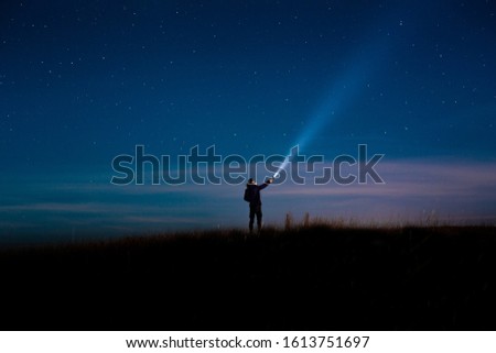 Milky Way.Long exposure photography, a
 man holding a flashlight and illuminating the sky full of stars. Image soft focus and noise due to long expose and high iso.