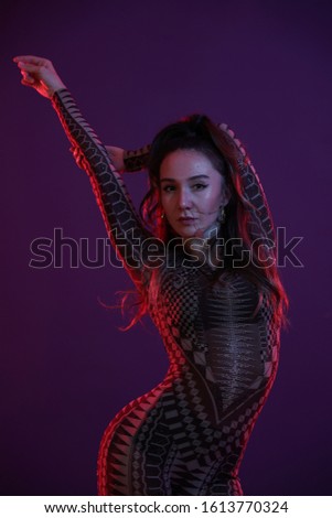 portrait of dancer girl in black clothes in front of purple background in the studio