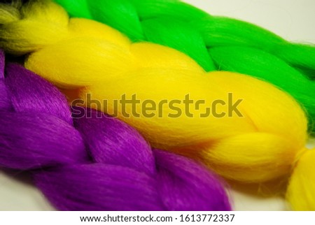 Kanekalon. Colored artificial hair strands. Synthetic hair materials for weaving African braids zizi. Close-up of bright colored hair. Overhead locks. Background for business cards. Yellow, green.