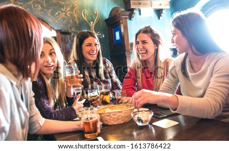 Happy women drinking beer at brewery restaurant - Female friendship concept with young girlfriends enjoying time together and having genuine fun at cool vintage pub - High iso image with soft focus