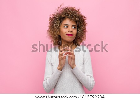 young african american woman scheming and conspiring, thinking devious tricks and cheats, cunning and betraying against pink wall