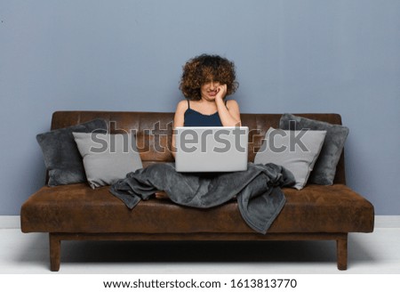 young pretty woman at home, sitting on a sofa with a laptop