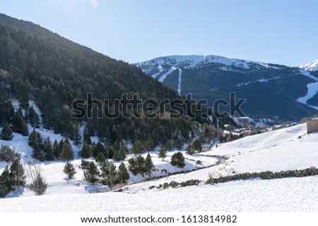 snow in the landscape and snowy mountains in Andorra, with some houses between the roads of the Pirieo