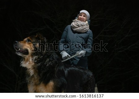 girl with a German shepherd walking on a winter night in the Park. Photo on the background of a dark forest.