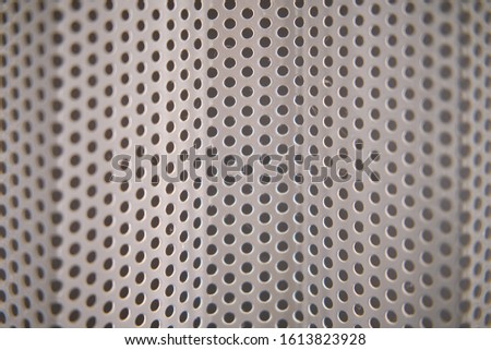 Background in the form of a curved grid with round holes, close-up