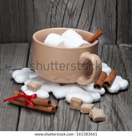 Mug of hot chocolate with marshmallows and cinnamon sticks on a dark wooden background