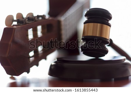 Judge's gavel and guitar. Concept of entertainment lawsuit, music piracy and copyright protection Royalty-Free Stock Photo #1613855443