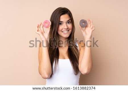 Teenager girl over isolated background holding donuts