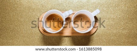 Fresh cup espresso coffee with milk on golden color bright paper. Food background. Top view. Flat lay. Minimalism