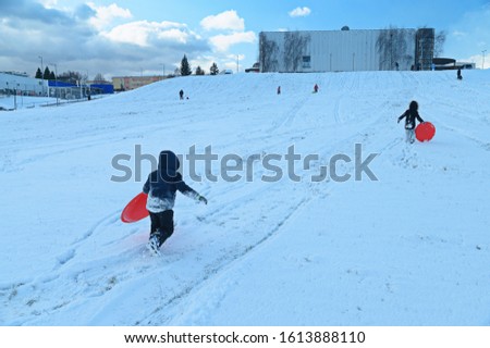 Children sledding in winter city. Fun on Winter holidays, holiday for children in winter. Winter city park.