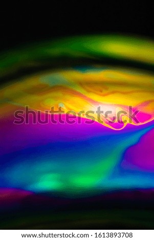 Macro of part of soap sphere on black background. The colors of the rainbow predominate
