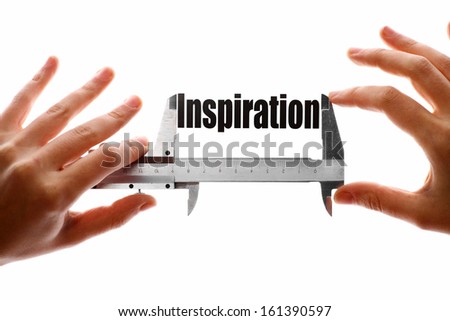 Two hands holding a caliper, measuring the word "Inspiration".