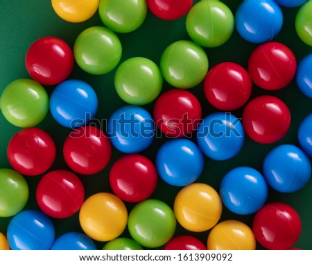 Multi-colored plastic balls on a green background top view, high resolution. 