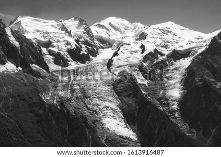Beautiful Alpine landscape with snow  covered Mont Blanc mountain and ice glacier at summer. France nature tourism background. Eco-planet, climate change concepts. Black white historic photo. 