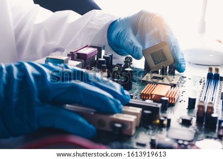 The technician laying a CPU on the computer's motherboard socket. the concept of computer, service, electronics, hardware, repairing, upgrade and technology.