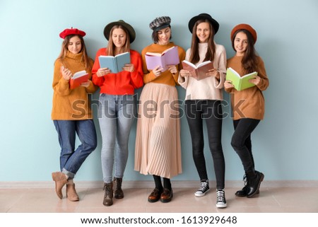 Young women with books near color wall