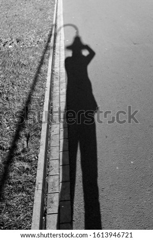 selfies with a shadow and a street lamp like a hat in street photography. black and white street photography. something in nothing.