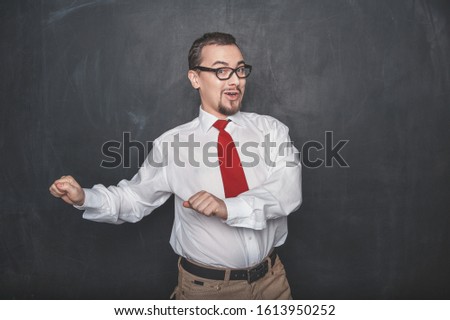 Funny young handsome man dancing on chalkboard background