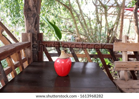 The red vase made of ceramics placed on a wooden table in the restaurant is a simple and beautiful design that looks comfortable.