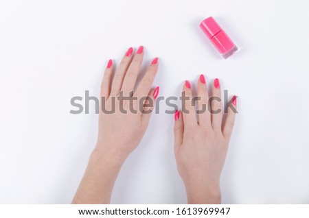 woman's hand with pink nail polish on white background