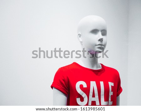 Female mannequin in a shop window on the background of the inscription sale.