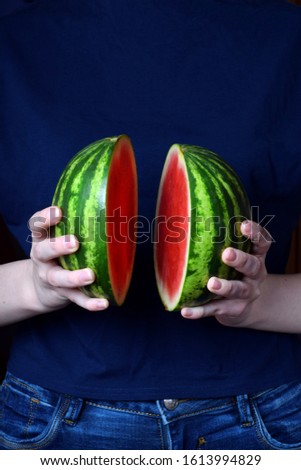 Mini watermelon cut into two halves held in woman hands 
