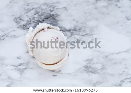 Flatlay view of one scoop of pink strawberry ice cream over a white and grey marble background texture. Top view.