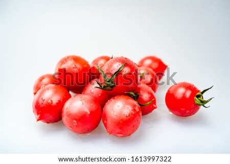 A pile of red cherry tomatoes against a white background