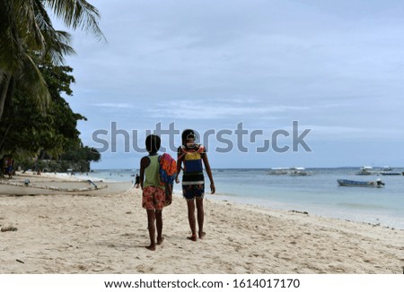 black children walk along the beach on a tropical island in the philippines