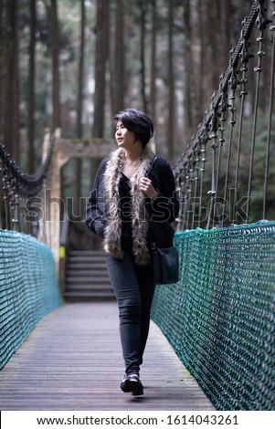 asian girl walking on wooden  pathway in forest